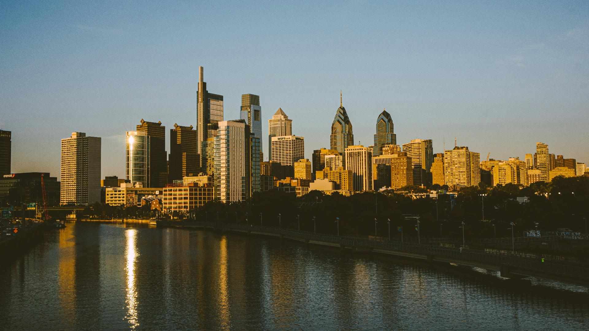 Philadelphia skyline at golden hour with waterfront reflection